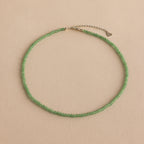 The Tiny Jade Choker Necklace in Silver features delicate green jade beads and a silver clasp with extender, shown on a beige background.