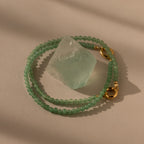 The Beaded Jade Clasp Bracelet features green beads and gold clasps, beautifully highlighting a translucent jade stone—an elegant accessory to pair with your favorite jewelry.