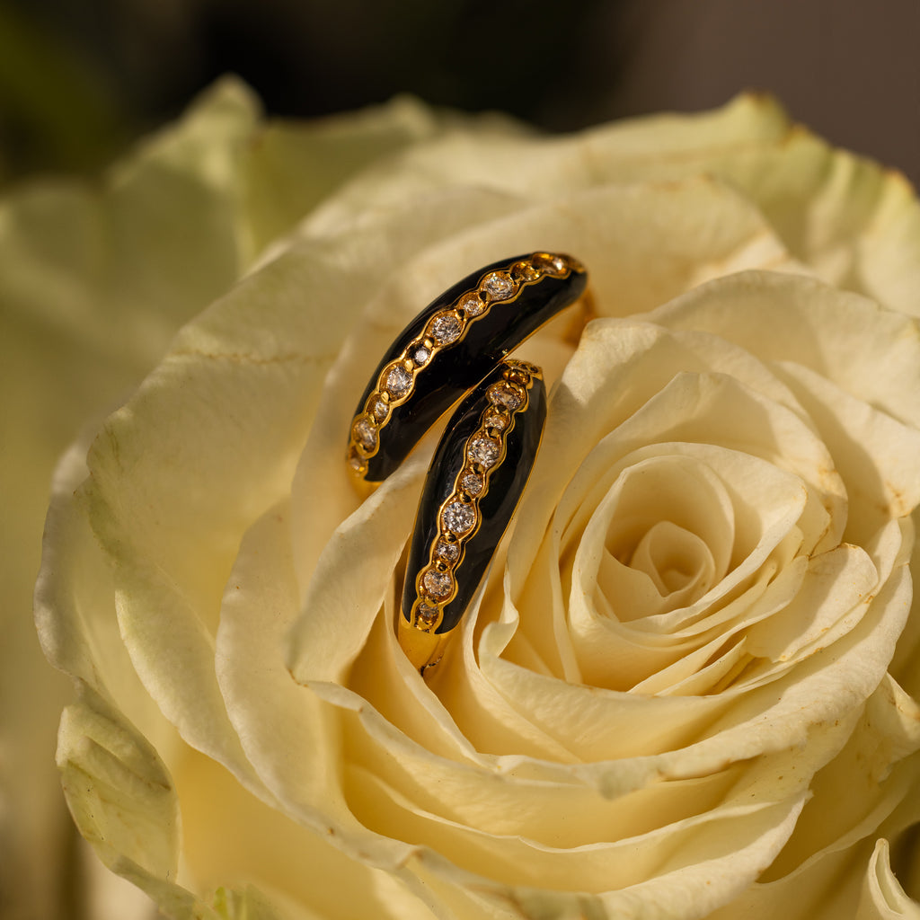 Noir Pave Dome Hoops in 18K Gold, adorned with enamel black accents and diamonds, rest delicately on pale yellow rose petals, making these statement earrings truly unforgettable.