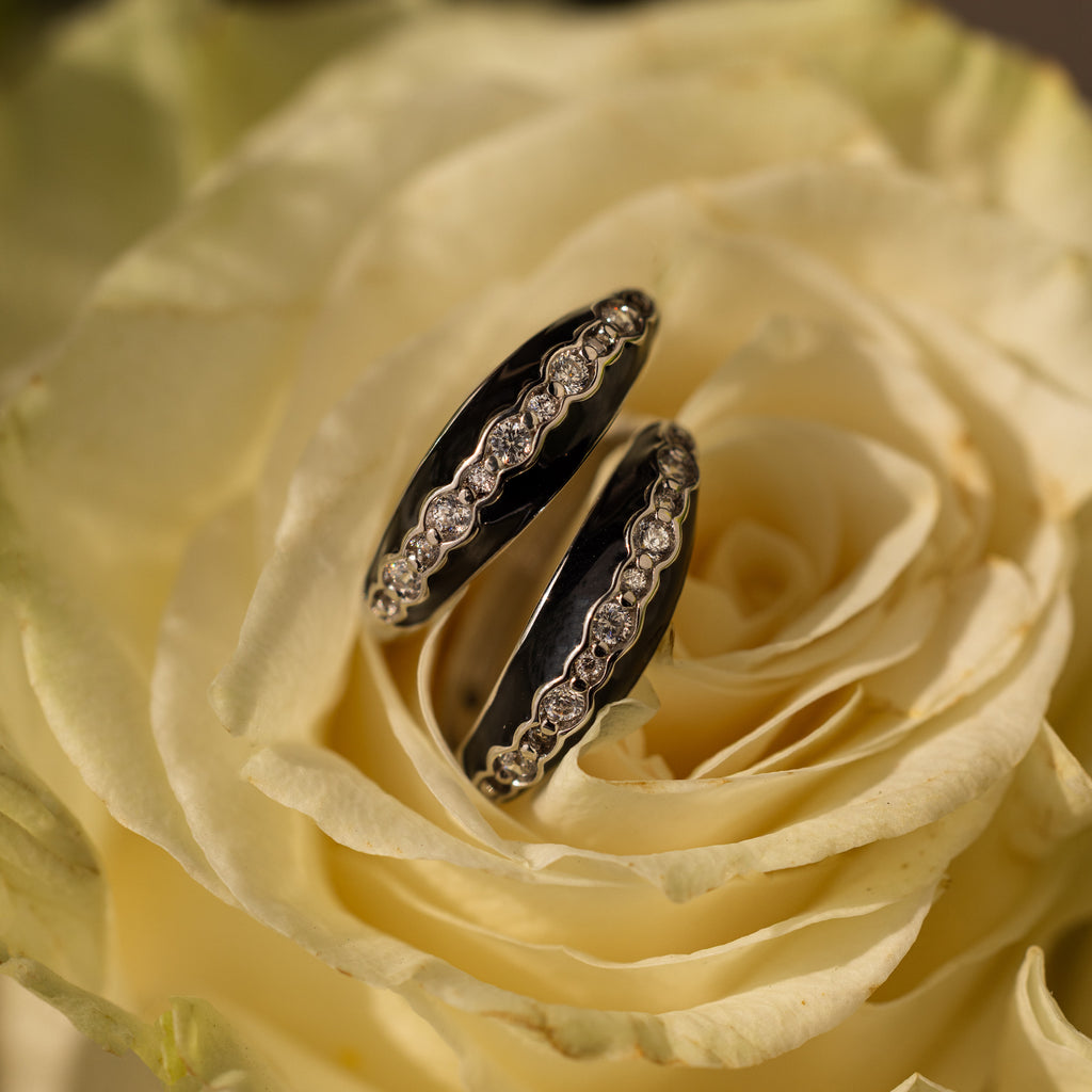 Two Noir Pave Dome Hoops in Silver with diamond details rest on pale yellow rose petals, creating a stunning statement earring pair.