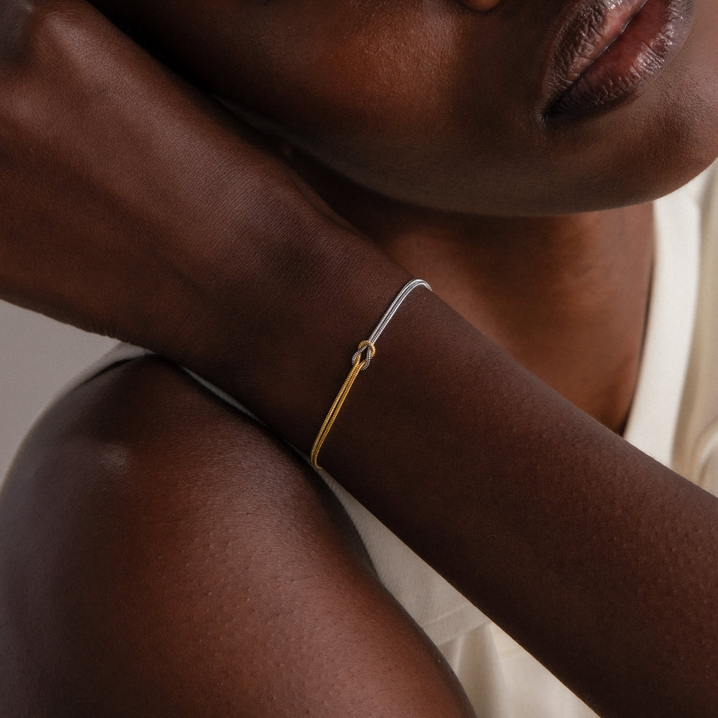 Close-up of a woman wearing the Mixed Metal Knot Bracelet, showcasing intertwined gold and silver snake chains that capture modern minimalism.