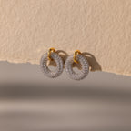 Mixed Metal Pave Circle Studs adorned with sparkling stones, displayed on a textured beige surface.