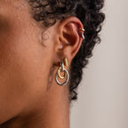 Close-up of an ear adorned with the Mixed Metal Linked Earrings in contemporary gold and silver design, styled on short, curly hair.