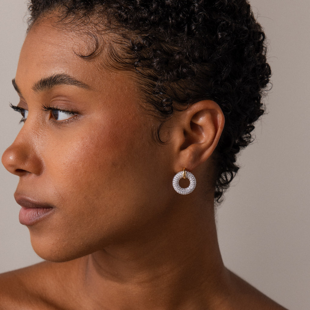 Woman with short curly hair wears Mixed Metal Pave Circle Studs, gazing to the left as the round, sparkly earrings catch the light.