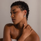 Woman with short curly hair poses with eyes closed, hand on neck, wearing Mixed Metal Pave Circle Studs and a strapless top.