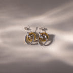 Mixed Metal Linked Earrings in gold and silver, featuring a contemporary interlocking hoop design, displayed on a neutral textured surface with soft shadows—ideal for achieving a modern mixed metal style.