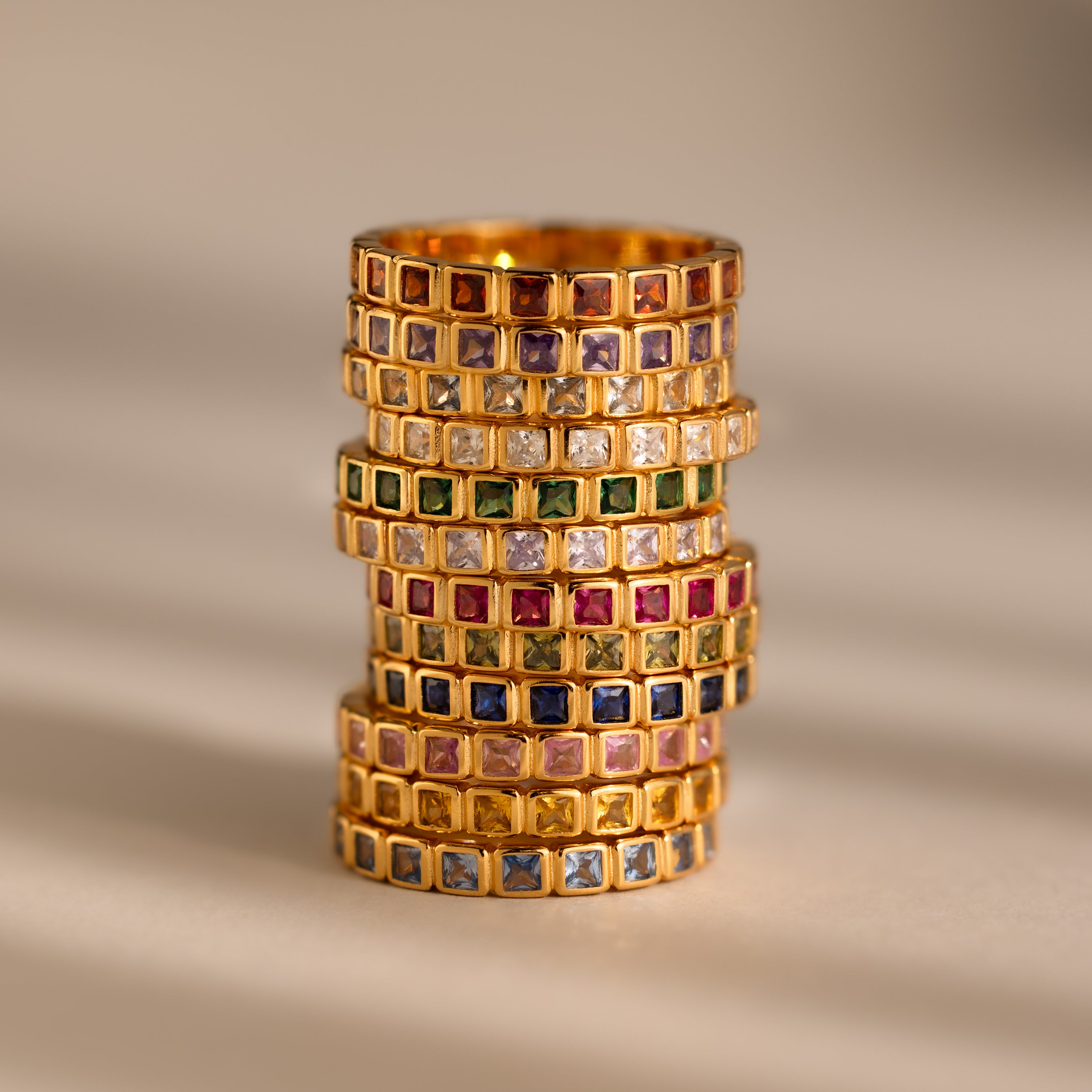 The Eternity Bezel Garnet Ring features a square-cut gemstone in a sleek bezel setting, its rich color standing out against a neutral backdrop.