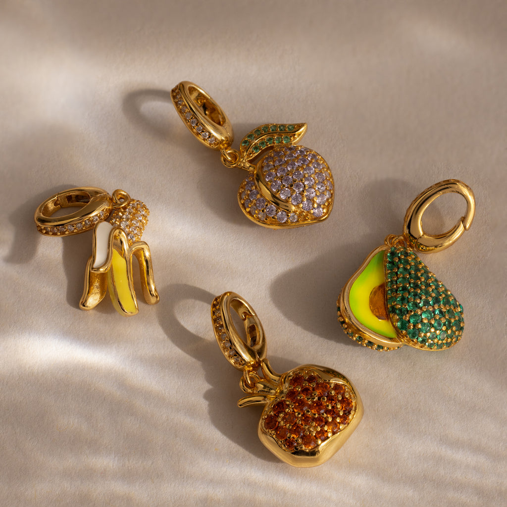 The Garnet Pomegranate Charm features a gold fruit-inspired design accented with vibrant pavé stones—a dazzling, eye-catching piece for any jewelry collection.
