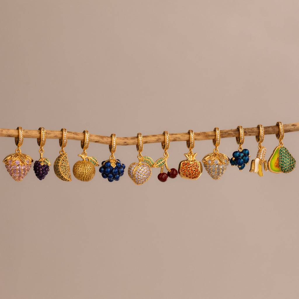 The Pink Tourmaline Raspberry Charm features a gold fruit design with pavé stones, adding a playful, sparkling touch to any jewelry collection.