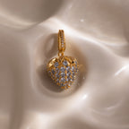 Aquamarine Blue Raspberry Charm with pavé stones and small clear gemstones on a smooth, cream-colored surface—a strikingly elegant piece to enhance any jewelry collection.