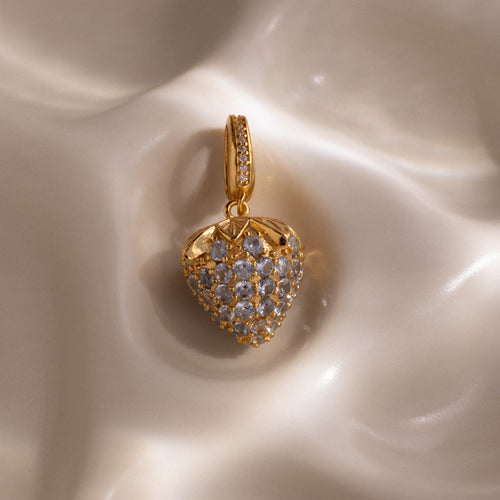 Aquamarine Blue Raspberry Charm with pavé stones and small clear gemstones on a smooth, cream-colored surface—a strikingly elegant piece to enhance any jewelry collection.