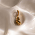 The Peridot Lime Charm, shaped like a lemon slice with pavé stones, sparkles atop creamy fabric—a standout piece from our jewelry collection.
