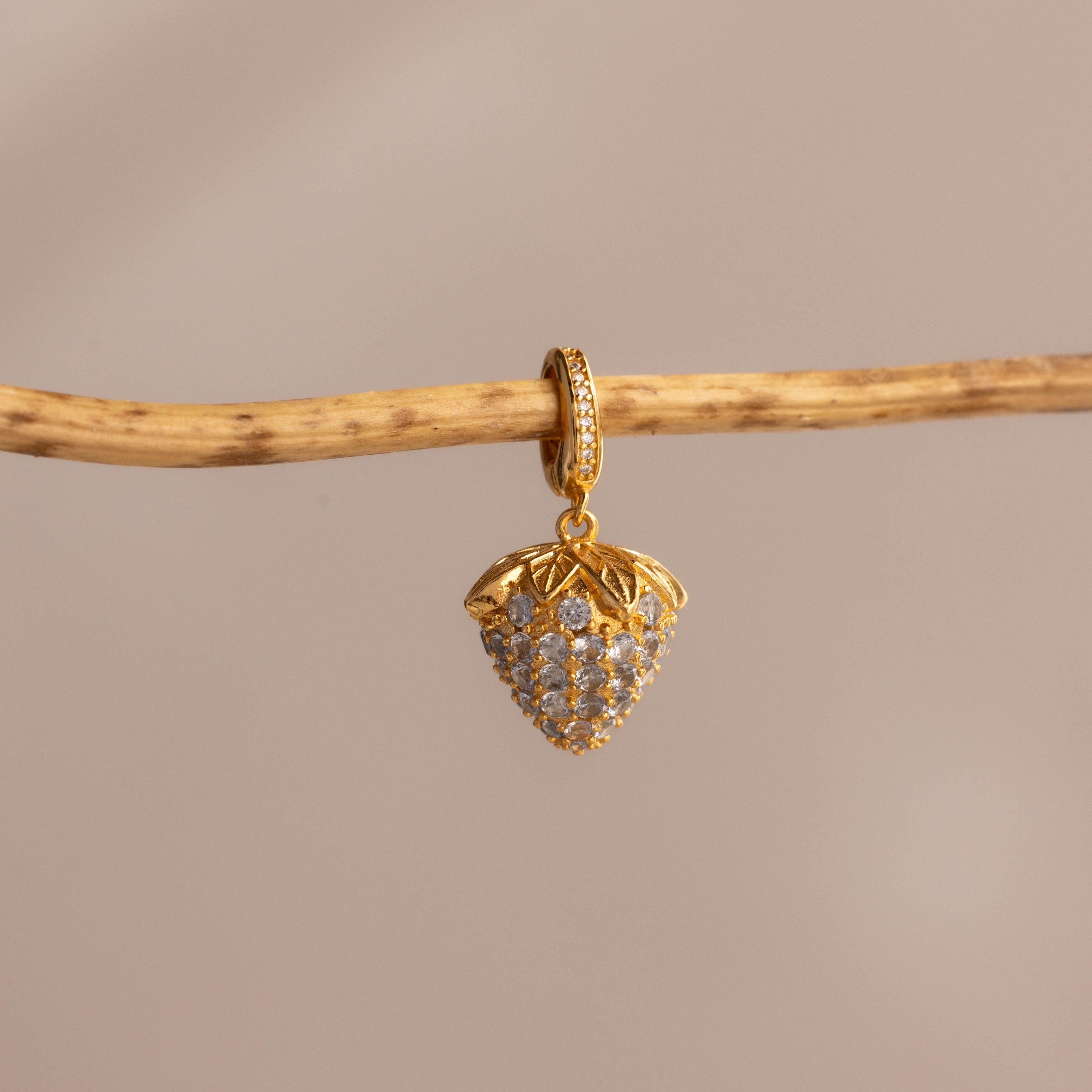 The Aquamarine Blue Raspberry Charm features sparkling pavé stones and a playful design, hanging elegantly against a neutral background—an eye-catching addition to any jewelry collection.