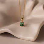 Ombre Emerald Flower Necklace: Gold chain necklace featuring a square green gemstone pendant, displayed on soft beige fabric.