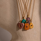 Five Amethyst Crystal Necklaces with gold chains and gemstone pendants display elegant birthstone jewelry against a beige surface.