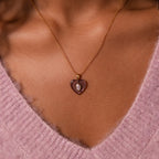 An Alexandrite Crystal Necklace is worn over a pink fuzzy V-neck sweater.