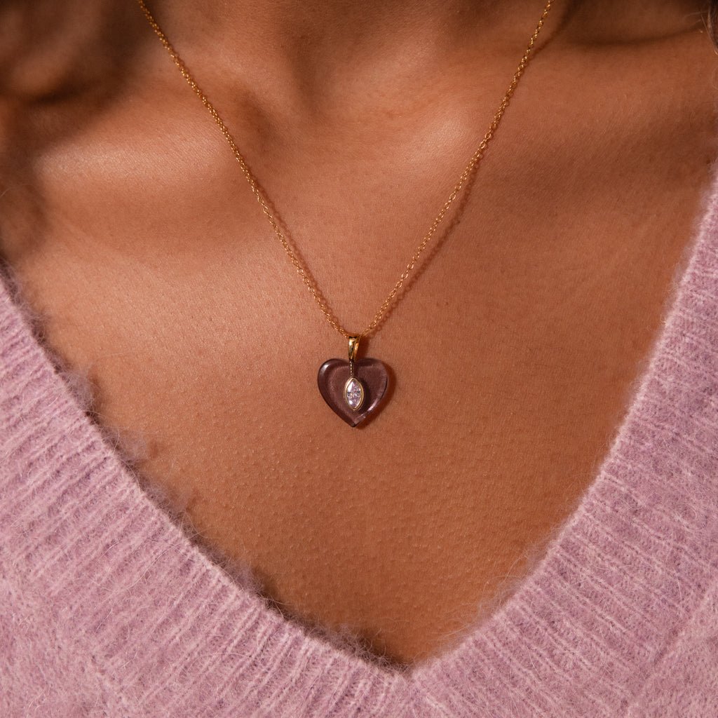 Emerald Crystal Necklace with a gold chain and heart-shaped pendant, styled over a pink fuzzy V-neck sweater.