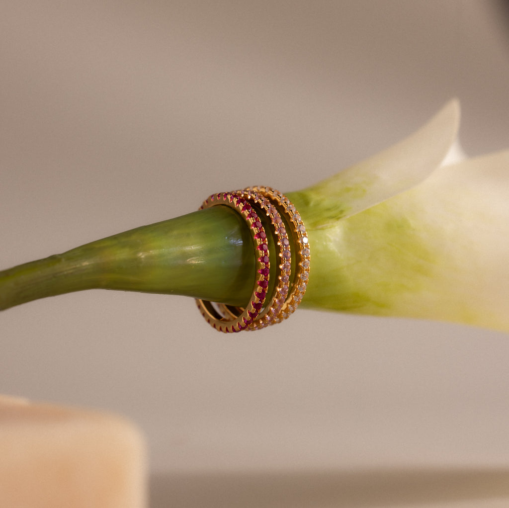 Endless Eternity Pink Tourmaline Ring stacked on a green flower stem against a soft, neutral background.