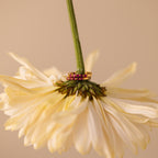 The Inside Out Ruby Huggies, adorned with vibrant red gemstones, rest elegantly on the green stem of an upside-down pale yellow flower.
