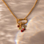 The Square Bezel Birthstone Charm rests on a light surface with a rainbow reflection, making it perfect for those who love gemstone jewelry.