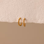 The Inside Out Topaz Huggies are small gold gemstone earrings with embedded stones, ideal for stacking, shown on a textured off-white surface.
