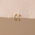 Inside Out Aquamarine Huggies: Gold hoop earrings featuring small blue aquamarine stones. Perfect for stacking or wearing solo, shown on a textured beige surface.