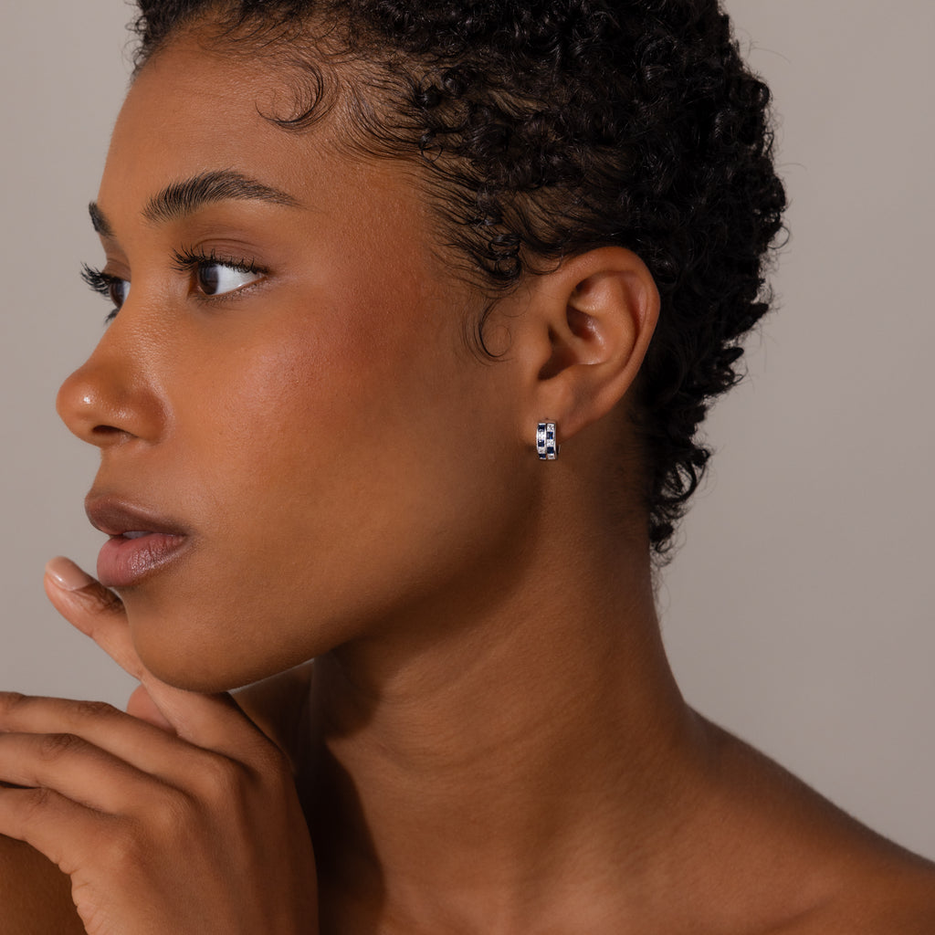 Woman with short curly hair wears Royal Blue Checkered Huggies in sterling silver, gazing thoughtfully to the side.