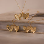 Five Organic Heart Locket Necklaces in 18K Gold, engraved and displayed on a closed book against a neutral background—a timeless keepsake jewelry piece.