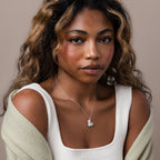 Woman with wavy hair wearing a white top, light sweater, and the Organic Heart Locket Necklace in Sterling Silver—a timeless keepsake jewelry piece.
