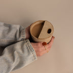 Hands with painted nails hold the Everyday Ceramic Mug, featuring a unique lid and speckled glaze, against a beige background.
