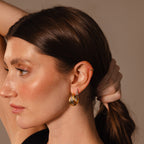 Woman with brown hair in a ponytail wears Intertwined Mixed Metal Hoops—gold and silver earrings—alongside a small gold ear cuff, shown in side profile.