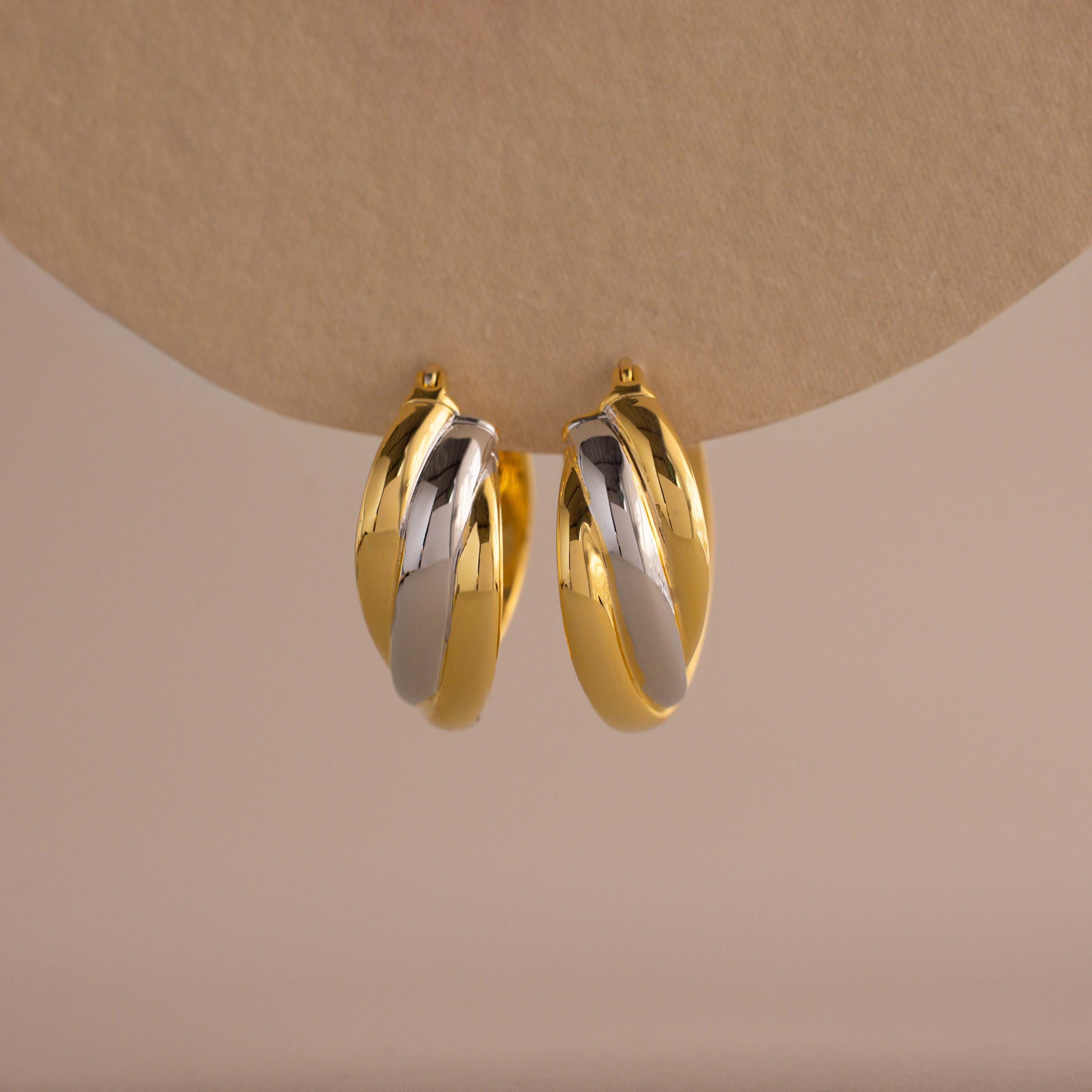 The Intertwined Mixed Metal Hoops feature gold and silver twisted hoops, creating a striking two-tone look against a neutral backdrop.