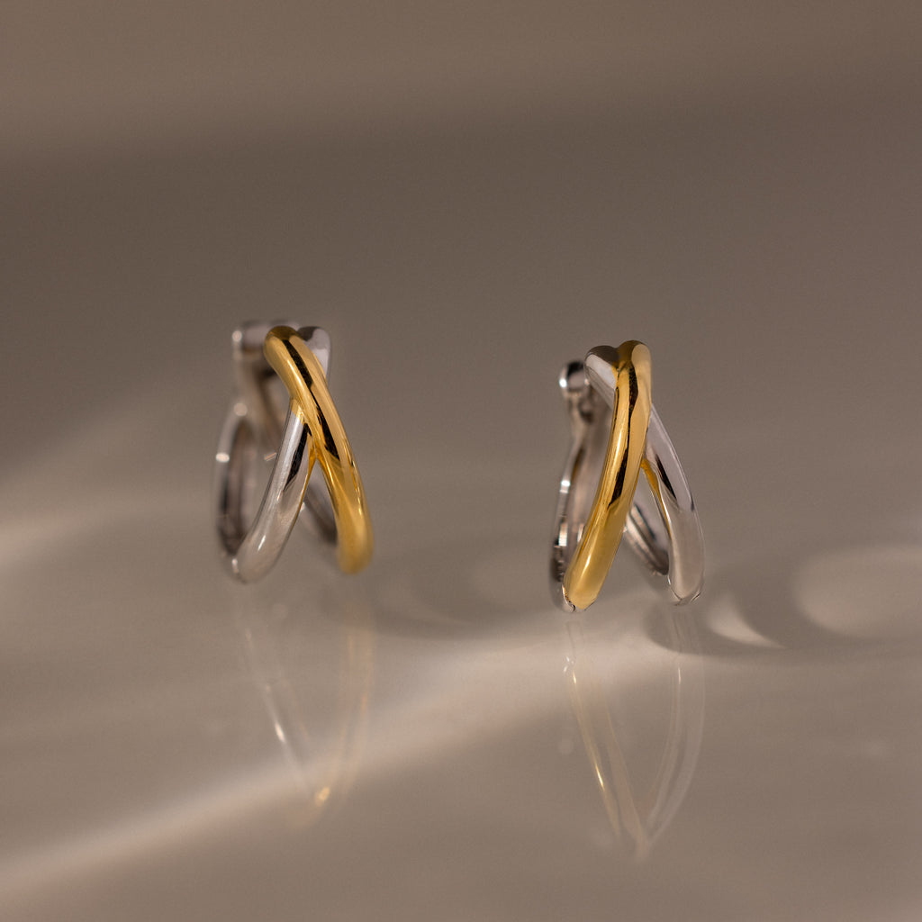Two intertwined hoops in silver and gold tones form the sculptural Laced Mixed Metal Huggies, creating a modern crossover design. Discover versatile elegance—these gold and silver earrings are perfect for any occasion.