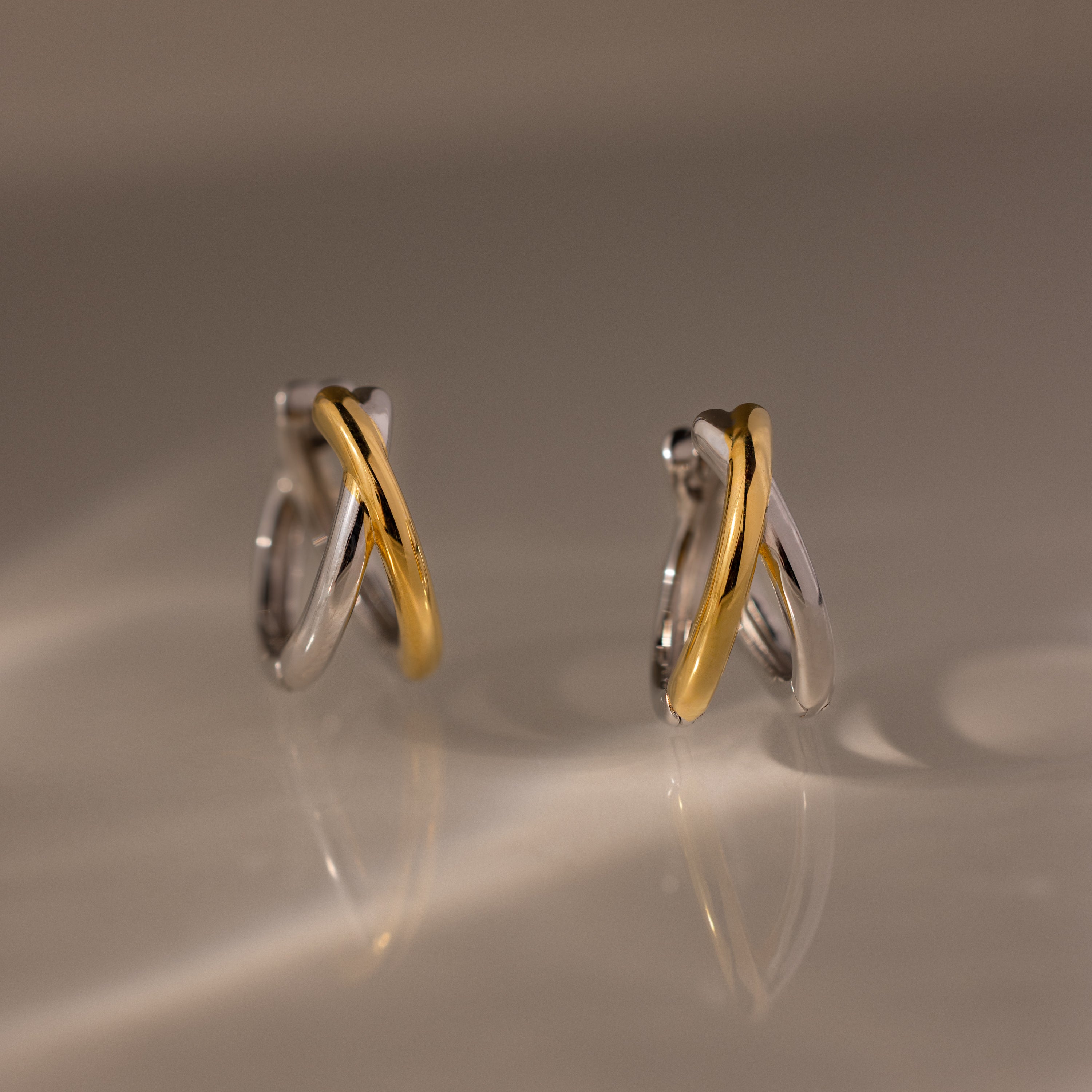 Two intertwined hoops in silver and gold tones form the sculptural Laced Mixed Metal Huggies, creating a modern crossover design. Discover versatile elegance—these gold and silver earrings are perfect for any occasion.