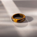 Experience earthy elegance with the Skinny Tiger's Eye Ring, featuring a rich brown gemstone set on a light gray surface in soft sunlight. Ideal as a stacking ring for a refined, natural look.