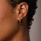 Close-up of a person's ear wearing Tiger's Eye Dome Drop Earrings in Sterling Silver, featuring round tiger's eye gemstones with silver hooks.