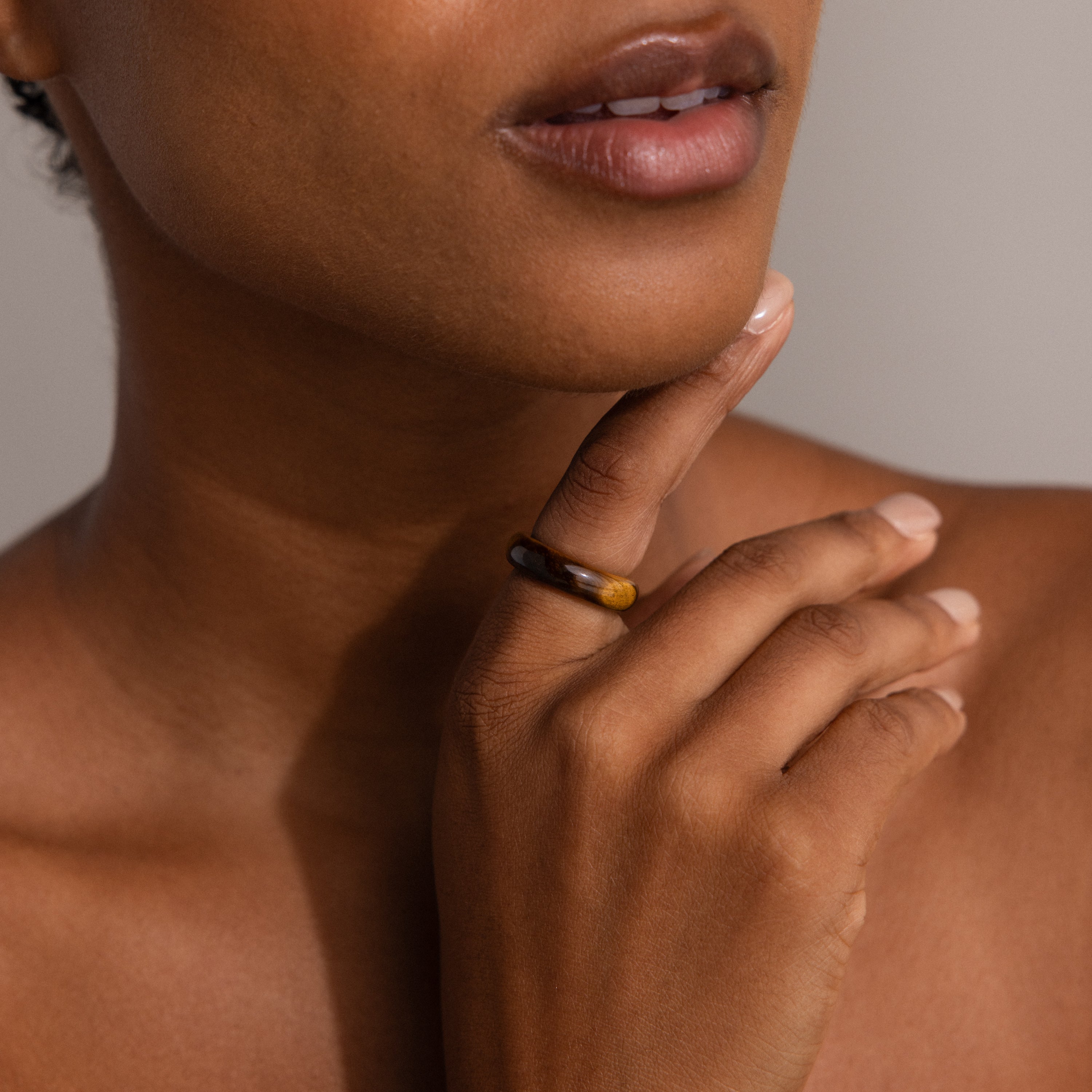 Close-up of a woman touching her chin, wearing the Skinny Tiger's Eye Ring on her finger, highlighting an earthy jewelry style.