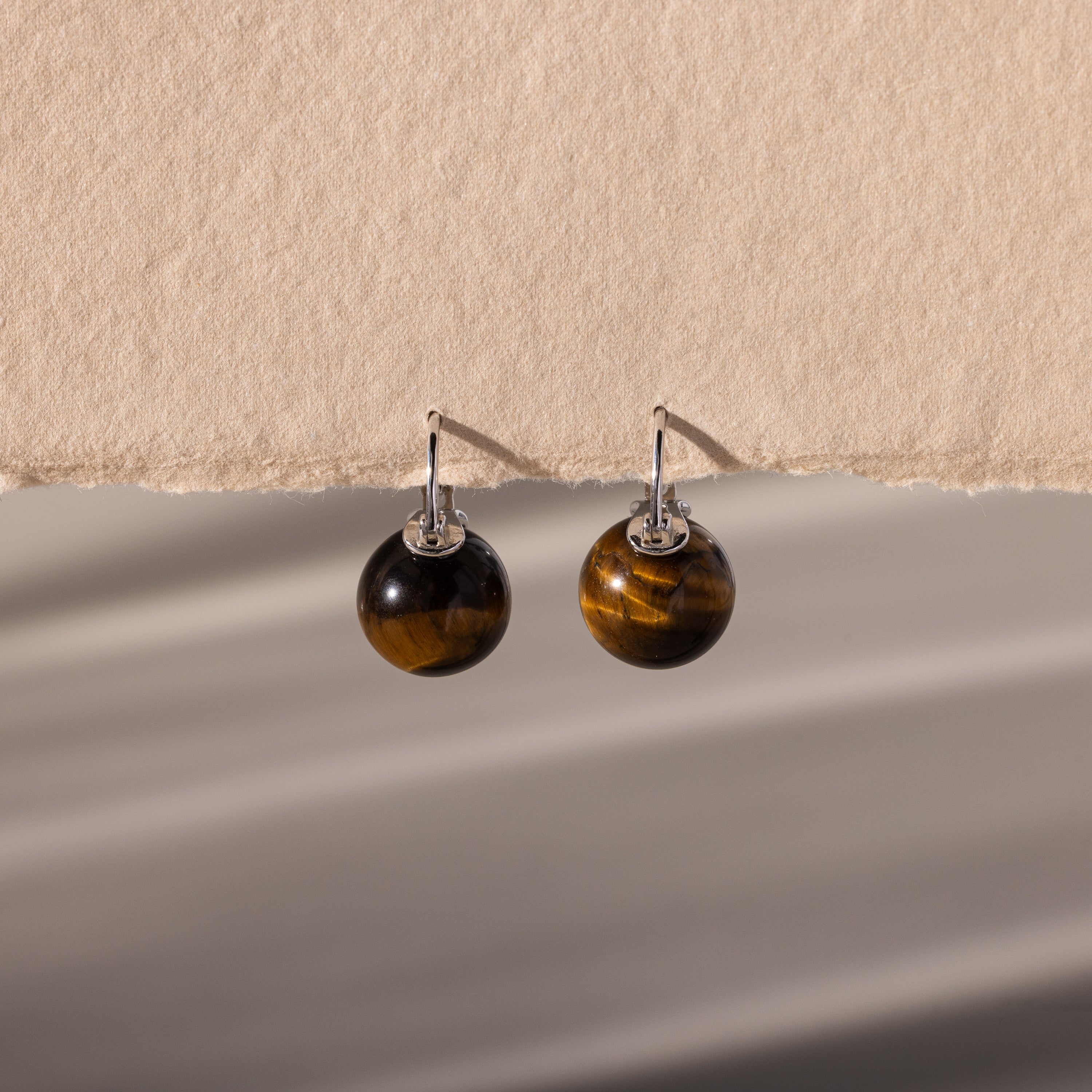 Tiger's Eye Dome Drop Earrings with silver hooks, featuring natural stone jewelry, displayed on a textured beige background.
