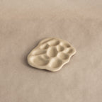 The Mini Organic Treasure Trove Jewelry Dish, in white ceramic, rests elegantly on a white surface—ideal as a mini jewelry holder or keepsake dish.