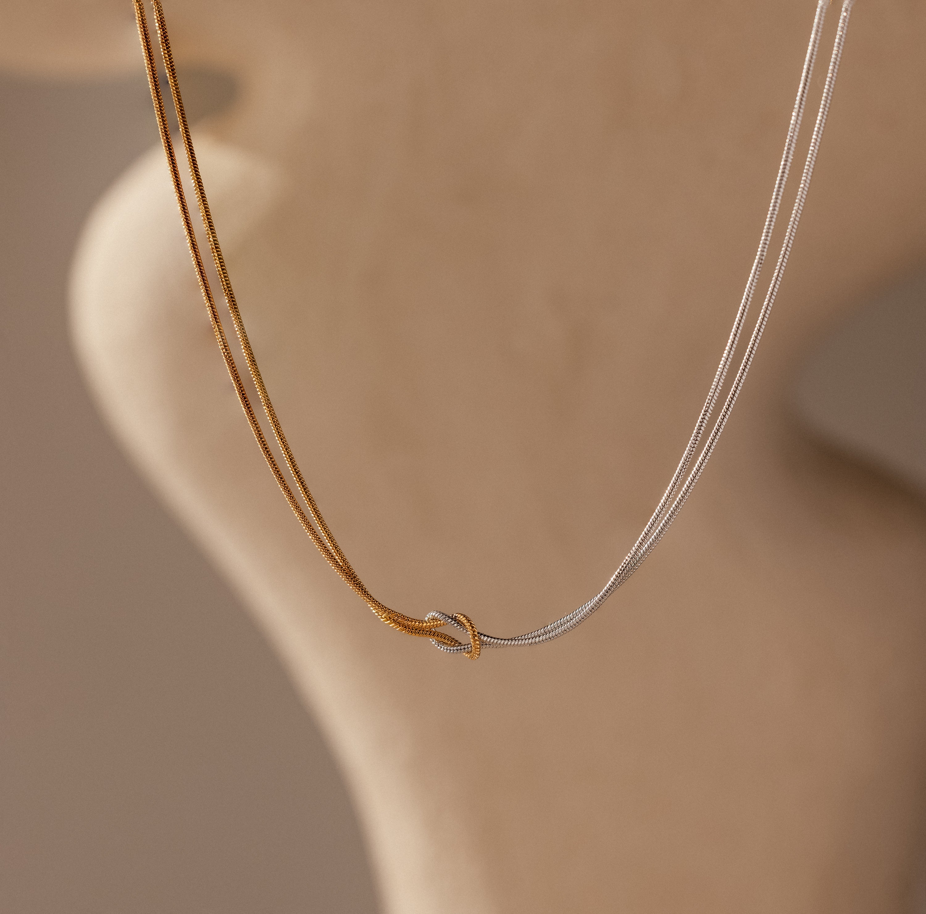 Two delicate gold and silver chains intertwine in the Mixed Metal Knot Necklace—a graceful symbol of everlasting love.