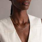 Close-up of a woman wearing a cream top and the Mixed Metal Knot Necklace, crafted with gold and silver chains that represent everlasting love.
