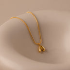 The Gemstone Bubble Initial Necklace features a gold letter pendant in a playful, abstract style on a smooth beige background—ideal for fans of personalized jewelry.