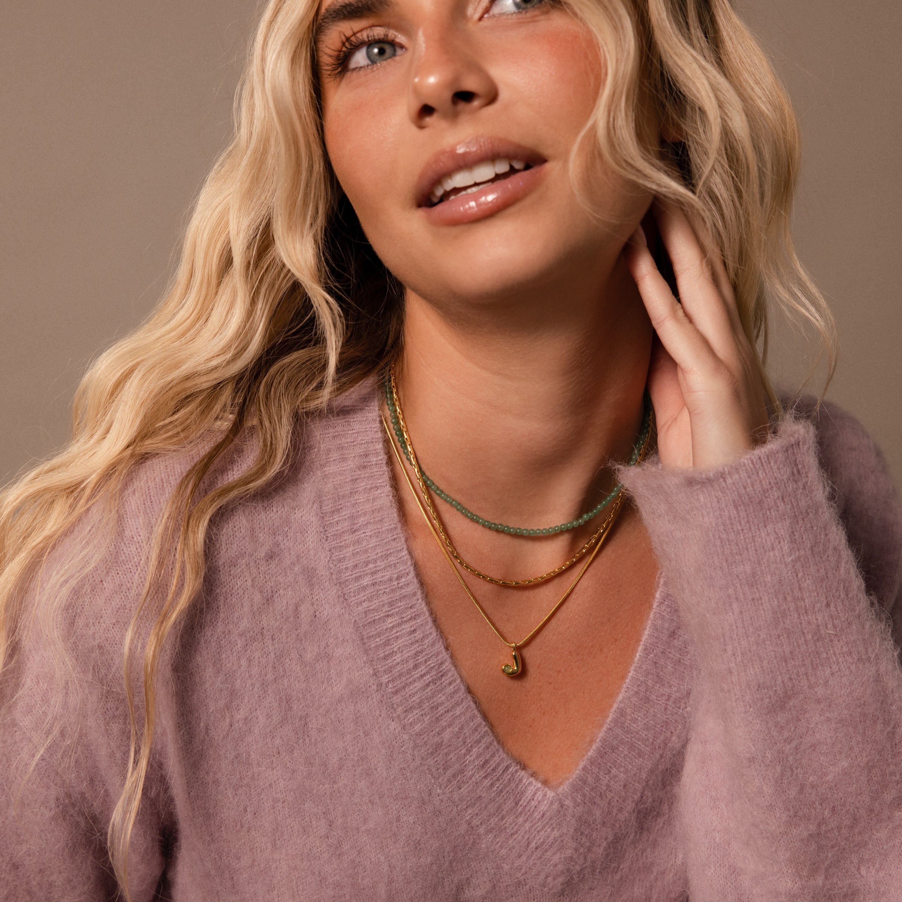 Woman with long blonde hair wears a fuzzy lavender sweater and the Gemstone Bubble Initial Necklace, gazing upward.