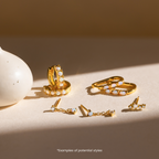 Four pairs of Mystery Jewelry gold and opal earrings are displayed on a light surface beside a white vase, each pair showcasing the whimsical charm and uniqueness of distinctive jewelry.