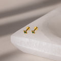 Gold geometric flat back emerald studs on a white surface