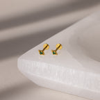 Gold geometric flat back emerald studs on a white surface