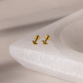 Gold geometric flat back peridot stud earrings on a white stone surface
