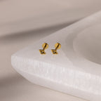 Gold geometric flat back peridot stud earrings on a white stone surface