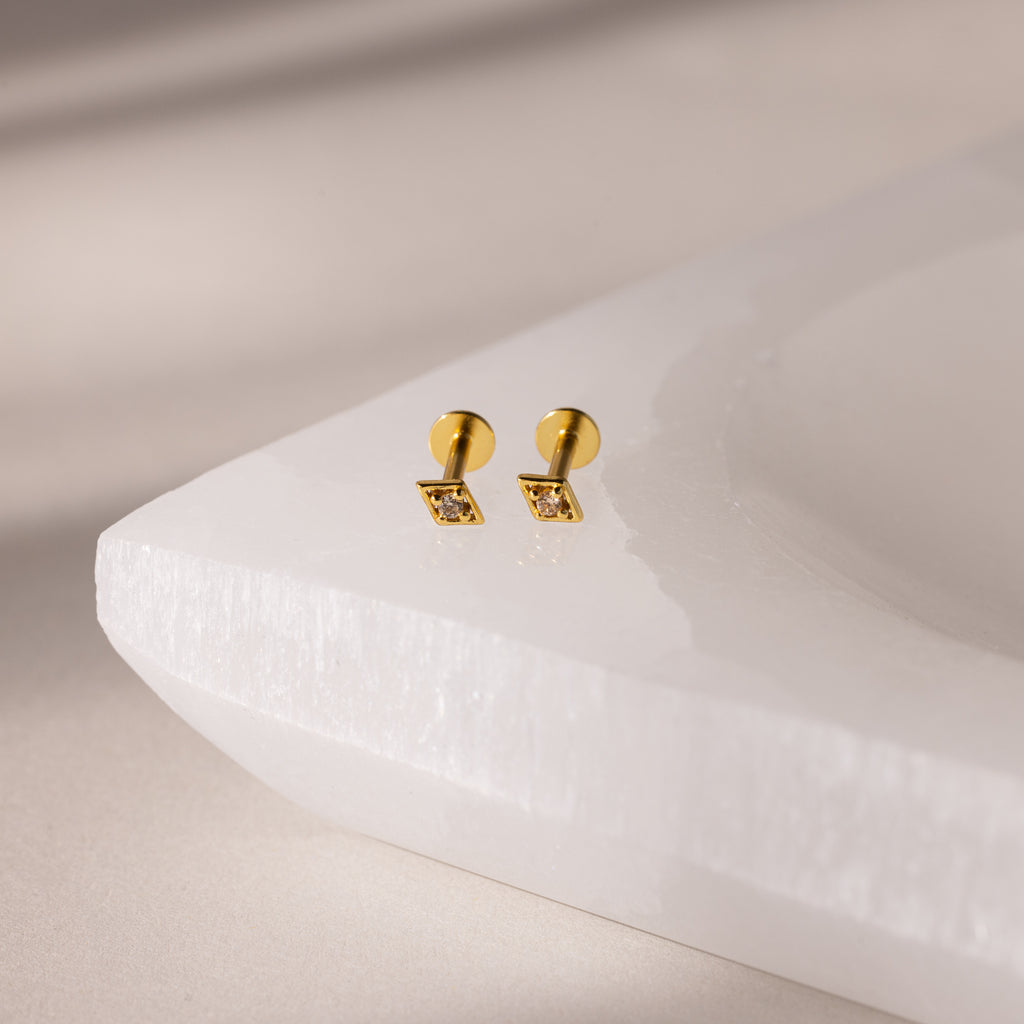 Gold geometric flat back topaz stud earrings with a neutral background