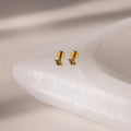 Gold geometric flat back aquamarine stud earrings on a textured white surface